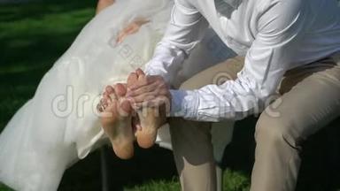 新郎新娘在公园。 男洗衣女`在婚礼当天光着脚走路后从草地上踩脚